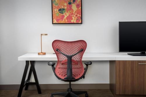 a desk with a red chair and a computer monitor at Hilton Garden Inn Missoula in Missoula