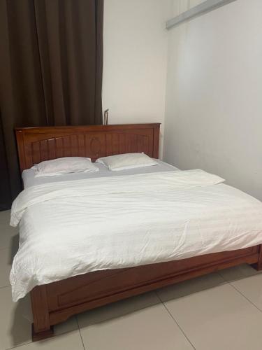 un letto con lenzuola e cuscini bianchi di Empire Homestay Melaka a Malacca
