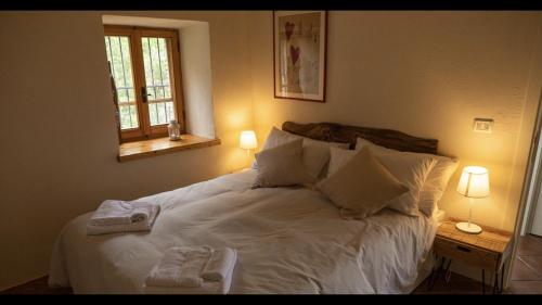 una camera da letto con un letto bianco e asciugamani di Al Castello di Elcito a San Severino Marche