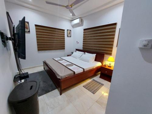 a small bedroom with a bed and a television at LAKESIDe VILLA in Accra