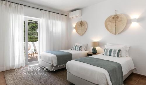 two beds in a white room with a window at Vilas Marrocha in Porches