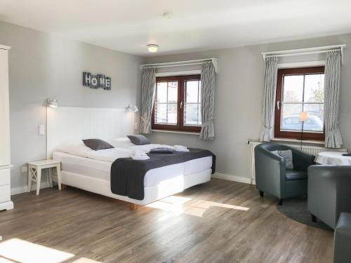 a bedroom with a bed and a couch and a chair at Landhaus Nordstern Hotel garni in Utersum