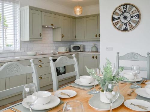 a kitchen with a table with chairs and a clock on the wall at Paxville in Gretna