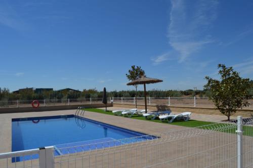 einen Pool mit Sonnenschirmen und Liegestühlen in der Unterkunft Casa Rural Finca Bella in San Clemente