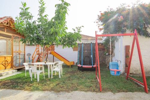 a yard with a table and chairs and a playground at Διαμέρισμα με αυλή στη Μέλισσα in Xanthi