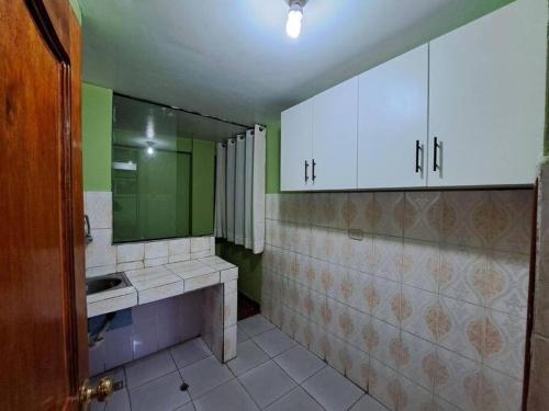 ein Badezimmer mit einem Waschbecken und grünen und weißen Schränken in der Unterkunft Julio Reyna Apartamento in Cusco