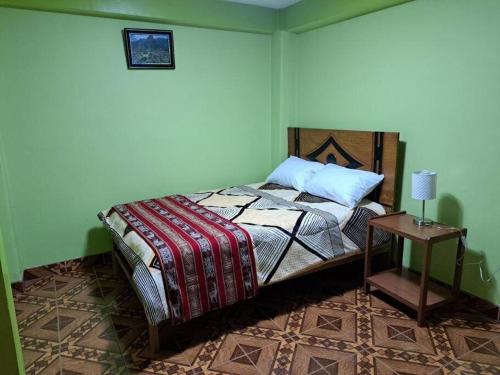 ein Schlafzimmer mit einem Bett und einem Tisch mit einer Lampe in der Unterkunft Julio Reyna Apartamento in Cusco