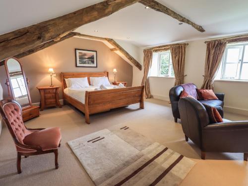 a bedroom with a bed and two chairs at Foxdene Cottage in Underbarrow