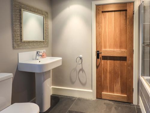 a bathroom with a sink and a toilet and a mirror at Foxdene Cottage in Underbarrow