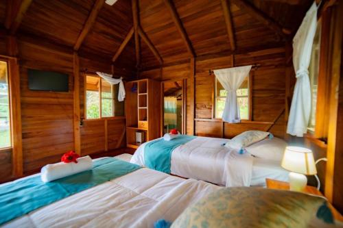 two beds in a room with wooden walls at Galapagos Cabañas Eden in Bellavista