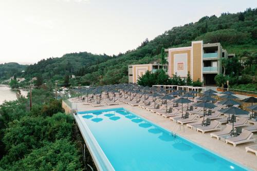 a pool with chairs and umbrellas next to a hotel at Kairaba Mythos Palace - Adults Only in Mesongi