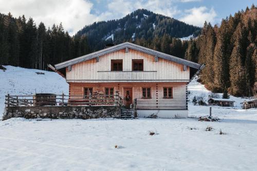 ein großes Holzhaus im Schnee mit Bäumen in der Unterkunft Hasenalm in Schliersee