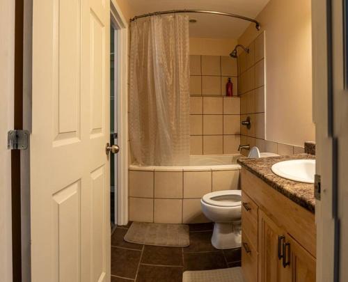 ein Badezimmer mit einem WC, einer Badewanne und einem Waschbecken in der Unterkunft Pink door-ed wonder in Grande Prairie