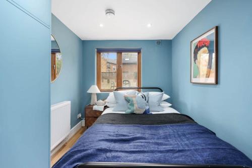 a blue bedroom with a bed and a window at Camden Garden Apartments in London