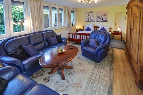 sala de estar con sofás azules, mesa y cama en Ferienwohnung mit ländlichem Charme, en Rodgau