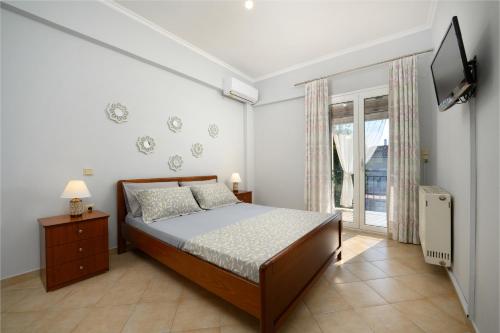 a bedroom with a bed and a tv and a window at Xenia's Apartments in Alepou in Corfu