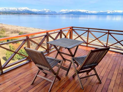a table and two chairs on a deck with a view of the water at Blue Aparts Dina Huapi Bariloche in Dina Huapi