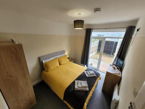 um quarto com uma cama amarela e uma janela em Cosy room in a stunning location em Llandrillo-yn-Rhôs