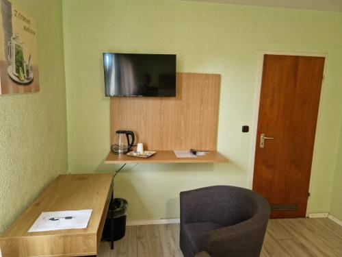 een kamer met een tafel, een stoel en een televisie bij Hotel PB in Goslar