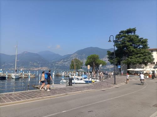 un grupo de personas caminando por una acera cerca de un cuerpo de agua en Beth House, en Iseo