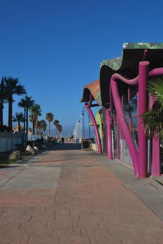 a boardwalk with a bridge in the background and palm trees at Una ventana al Mar en Málaga in Málaga