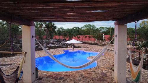 a patio with a hammock and a pool at Cabañas HUNAB KU 21 