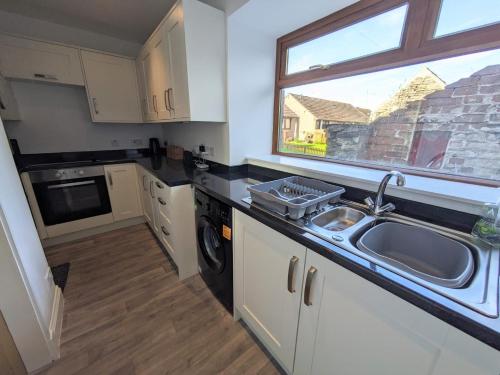 a small kitchen with a sink and a window at 2 Bedroom Townhouse with Seaview on the NC500 Wick in Wick