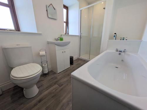 a bathroom with a toilet and a tub and a sink at 2 Bedroom Townhouse with Seaview on the NC500 Wick in Wick