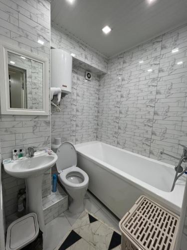 W łazience znajduje się biała wanna, toaleta i umywalka. w obiekcie Байзак- батыра 187 w mieście Taraz