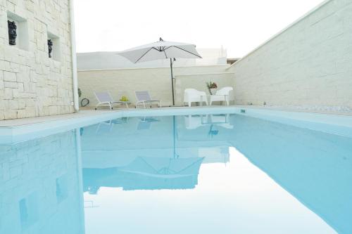 a swimming pool with an umbrella and chairs and a table and an umbrella at Vela Bianca Marzamemi in Marzamemi