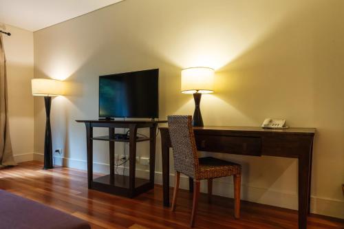 a room with a desk with a television and two lamps at Loi Suites Iguazu Hotel in Puerto Iguazú