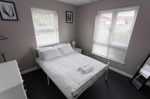 a bedroom with a white bed with two windows at Apartment 4 Oak Villa in Belfast