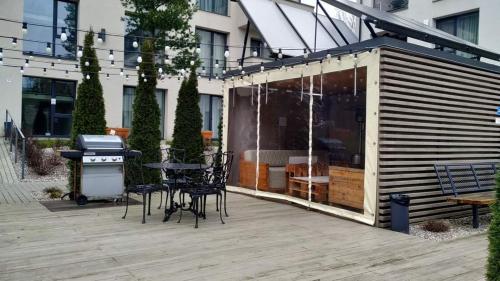 een patio met een grill en tafels en stoelen bij Studija su baseinu Malūno Vilos in Palanga