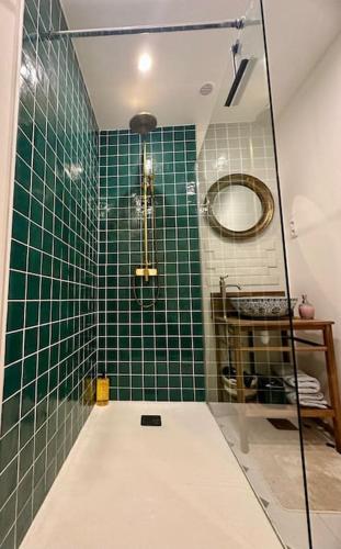La salle de bains est pourvue de carrelage vert, d'une douche et d'un miroir. dans l'établissement Appartement au coeur de la Ville Fortifiée, à Boulogne-sur-Mer