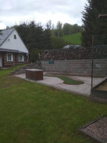 a yard with a retaining wall and a fence at Chalupa pod sjezdovkou in Chvaleč