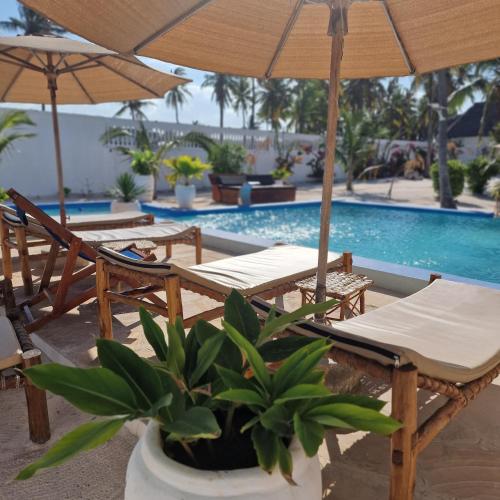 a pool with chairs and umbrellas next to a pool at TIANDE Boutique Hotel in Pwani Mchangani