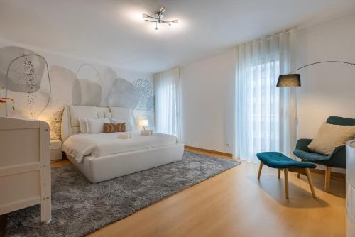 a white bedroom with a white bed and a blue chair at Charm 3BDR Apartment W/Balcony by LovelyStay in Lisbon