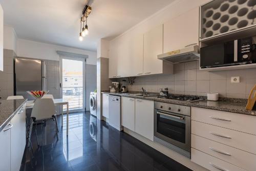 a kitchen with white cabinets and a counter top at Charm 3BDR Apartment W/Balcony by LovelyStay in Lisbon