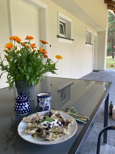 a plate of pasta on a counter with a vase with flowers at Agroturystyka u Sylwii in Majdan Sopocki