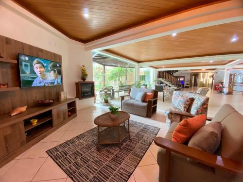 a living room with a couch and a flat screen tv at Morada do Mar Hotel in Bombinhas