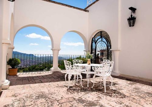 a patio with white chairs and a table with a view at Casa Estrella de la Valenciana Hotel Boutique in Guanajuato