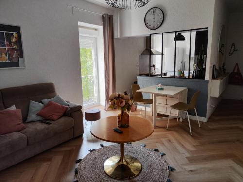 ein Wohnzimmer mit einem Sofa und einem Tisch in der Unterkunft LE PETIT ANGLE APPARTEMENT 2 Pièces, plein centre ville, près de la gare jusqu'à 4 personnes in Bellegarde-sur-Valserine