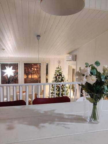 a vase of flowers on a table with a christmas tree at Sunstar Villa in Rovaniemi