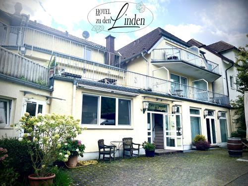 a white house with a table and chairs in front of it at Hotel zu den Linden in Wachtberg