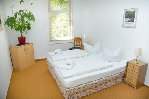 a room with two white beds and a plant at Waldhotel Friedrichroda in Friedrichroda