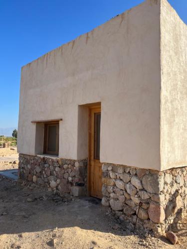 ein kleines Gebäude mit einer Steinmauer und einer Tür in der Unterkunft Farm’s guest room in Nuweiba