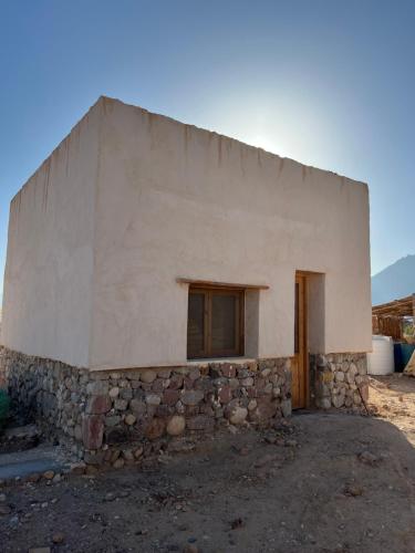 un pequeño edificio de piedra con una pared de piedra en Farm’s guest room, en Nuweiba