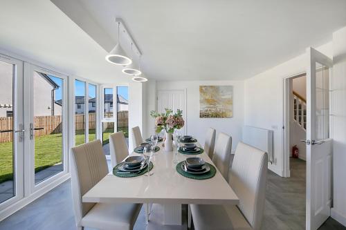 uma sala de jantar branca com uma mesa e cadeiras brancas em Fern Place Villa - Grampian Lettings Ltd 