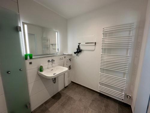ein weißes Badezimmer mit einem Waschbecken und einem Spiegel in der Unterkunft EBM-Apartments Altenmünster mit Wallbox in Altenmünster