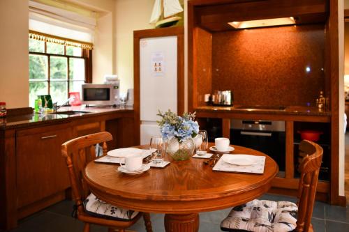 MayboleにあるCloncaird Castle Estate Cottagesのキッチン(木製のテーブル、椅子、花付)
